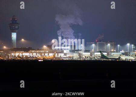 Nachtansicht des Flughafens Amsterdam Schiphol AMS mit Flugzeugen vor den Toren. 14 Fälle der neuen COVID-19-Variante Omicron wurden in den Niederlanden von Passagieren bestätigt, die aus Südafrika in die niederländische Stadt kamen. Mehr als 600 Passagiere wurden von den 2 Flügen getestet, wobei 61 positiv für Covid-19 bestätigt wurden. Die niederländische Polizei verhaftete zuvor zwei Passagiere, die sich in einem Quarantänehotel aufgehalten haben, als sie versuchten zu entkommen. Viele Länder haben Flüge nach Südafrika während einer bereits schwierigen Zeit mit der Coronavirus-Pandemie, die sich negativ auf die Luftfahrtindustrie auswirkte, eingestellt. Stockfoto