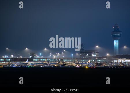 Nachtansicht des Flughafens Amsterdam Schiphol AMS mit Flugzeugen vor den Toren. 14 Fälle der neuen COVID-19-Variante Omicron wurden in den Niederlanden von Passagieren bestätigt, die aus Südafrika in die niederländische Stadt kamen. Mehr als 600 Passagiere wurden von den 2 Flügen getestet, wobei 61 positiv für Covid-19 bestätigt wurden. Die niederländische Polizei verhaftete zuvor zwei Passagiere, die sich in einem Quarantänehotel aufgehalten haben, als sie versuchten zu entkommen. Viele Länder haben Flüge nach Südafrika während einer bereits schwierigen Zeit mit der Coronavirus-Pandemie, die sich negativ auf die Luftfahrtindustrie auswirkte, eingestellt. Stockfoto