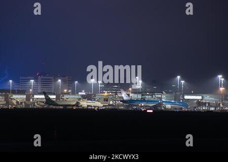 Nachtansicht des Flughafens Amsterdam Schiphol AMS mit Flugzeugen vor den Toren. 14 Fälle der neuen COVID-19-Variante Omicron wurden in den Niederlanden von Passagieren bestätigt, die aus Südafrika in die niederländische Stadt kamen. Mehr als 600 Passagiere wurden von den 2 Flügen getestet, wobei 61 positiv für Covid-19 bestätigt wurden. Die niederländische Polizei verhaftete zuvor zwei Passagiere, die sich in einem Quarantänehotel aufgehalten haben, als sie versuchten zu entkommen. Viele Länder haben Flüge nach Südafrika während einer bereits schwierigen Zeit mit der Coronavirus-Pandemie, die sich negativ auf die Luftfahrtindustrie auswirkte, eingestellt. Stockfoto