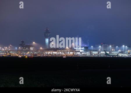 Nachtansicht des Flughafens Amsterdam Schiphol AMS mit Flugzeugen vor den Toren. 14 Fälle der neuen COVID-19-Variante Omicron wurden in den Niederlanden von Passagieren bestätigt, die aus Südafrika in die niederländische Stadt kamen. Mehr als 600 Passagiere wurden von den 2 Flügen getestet, wobei 61 positiv für Covid-19 bestätigt wurden. Die niederländische Polizei verhaftete zuvor zwei Passagiere, die sich in einem Quarantänehotel aufgehalten haben, als sie versuchten zu entkommen. Viele Länder haben Flüge nach Südafrika während einer bereits schwierigen Zeit mit der Coronavirus-Pandemie, die sich negativ auf die Luftfahrtindustrie auswirkte, eingestellt. Stockfoto