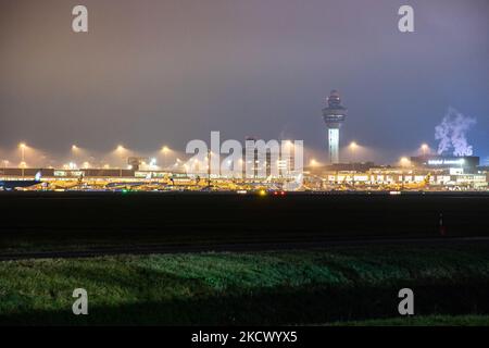 Nachtansicht des Flughafens Amsterdam Schiphol AMS mit Flugzeugen vor den Toren. 14 Fälle der neuen COVID-19-Variante Omicron wurden in den Niederlanden von Passagieren bestätigt, die aus Südafrika in die niederländische Stadt kamen. Mehr als 600 Passagiere wurden von den 2 Flügen getestet, wobei 61 positiv für Covid-19 bestätigt wurden. Die niederländische Polizei verhaftete zuvor zwei Passagiere, die sich in einem Quarantänehotel aufgehalten haben, als sie versuchten zu entkommen. Viele Länder haben Flüge nach Südafrika während einer bereits schwierigen Zeit mit der Coronavirus-Pandemie, die sich negativ auf die Luftfahrtindustrie auswirkte, eingestellt. Stockfoto