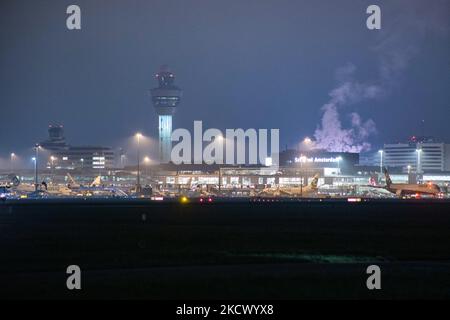 Nachtansicht des Flughafens Amsterdam Schiphol AMS mit Flugzeugen vor den Toren. 14 Fälle der neuen COVID-19-Variante Omicron wurden in den Niederlanden von Passagieren bestätigt, die aus Südafrika in die niederländische Stadt kamen. Mehr als 600 Passagiere wurden von den 2 Flügen getestet, wobei 61 positiv für Covid-19 bestätigt wurden. Die niederländische Polizei verhaftete zuvor zwei Passagiere, die sich in einem Quarantänehotel aufgehalten haben, als sie versuchten zu entkommen. Viele Länder haben Flüge nach Südafrika während einer bereits schwierigen Zeit mit der Coronavirus-Pandemie, die sich negativ auf die Luftfahrtindustrie auswirkte, eingestellt. Stockfoto