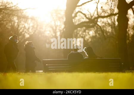 Menschen mit Gesichtsmasken zum Schutz vor dem Covid-19-Coronavirus wandern am 2. Dezember 2021 im nachmittäglichen Wintersonnenlicht durch den Green Park in London, England. (Foto von David Cliff/NurPhoto) Stockfoto