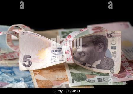 Foto Illustration von türkischen Lira-Banknoten auf schwarzem Hintergrund und einem Maßband als Symbol für die schrumpfende Wirtschaft und Währung. Die Lira erreicht ein neues Rekordtief, da die Währung die Verluste für den Handel über 13,73 pro US-Dollar und 15,51 Euro ausdehnte. Die türkische Lira rutscht auf ein Rekordtief, nachdem Präsident Erdogan die Leitzinspolitik verdoppelt hat. Illustration der türkischen Lira-Banknoten, die Währung der Türkei, in türkischer Sprache Türk Lira genannt, mit dem Zeichen: Und Code TRY oder TL. Auf der Vorderseite des Gesetzentwurfs sind Porträts von Mustafa Kemal Atatürk zu sehen. Amsterdam, Niederlande am 33. Dezember 2021. (Foto von Nicol Stockfoto