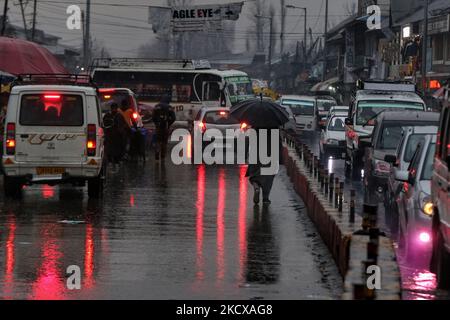 Am 05. Dezember 2021 bewegen sich Fahrzeuge bei Niederschlägen in Sovore, District Baramulla, Jammu und Kashmir, Indien. Da in höheren Regionen am Sonntag frischer Schneefall und Regen in die Ebenen einfallen, hat das Wetterministerium vorhergesagt, dass es in den nächsten 12 Stunden in Kaschmir keine größeren Wetteränderungen geben wird und dass ab heute Abend eine Verbesserung des vorherrschenden Zustands erwartet wird. (Foto von Nasir Kachroo/NurPhoto) Stockfoto