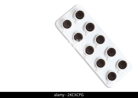 Kleine Kaffeetassen, die auf einem weißen, isolierten Pillenblister platziert werden. Medikamente und Kaffee-Interaktionskonzept. Stockfoto