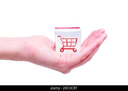 Spielzeug weißen Versandkarton mit einem Warenkorb-Symbol in der Hand isoliert auf weißem Hintergrund beschriftet. Stockfoto