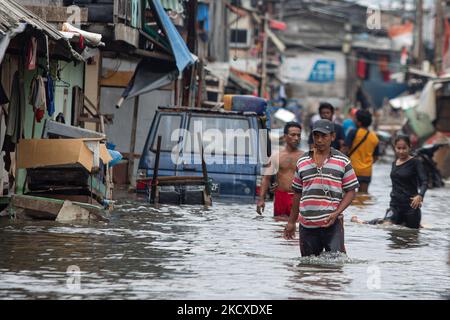 Am 7. Dezember 2021 waten Bewohner durch eine von Flutwellen überflutete Straße in Jakartas Küstengebiet, Muara Angke. Lokale Behörden prognostizierten, dass am 6. Und 9. Dezember hohe Gezeiten und starke Winde die Jakarta Bay Area und nördlich von W. Java treffen werden, was dazu führt, dass das Küstengebiet der Hauptstadt unter Wasser liegt und die Häuser beschädigt werden. Überschwemmungen durch den Überlauf von Meerwasser untergetaucht 15 Wohneinheiten in Nord-Jakarta und West-Jakarta. (Foto von Afriadi Hikmal/NurPhoto) Stockfoto