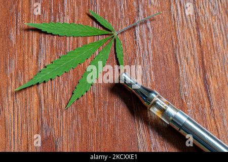 CBD-Verdampfer mit einem Hintergrund aus Cannabisblättern Stockfoto