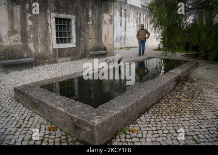 Eine Person geht in der Nähe eines der Brunnen im Aguas Livres Museumskomplex, Lissabon. 05. Dezember 2021. Das Aquädukt Ãguas Livres oder das Freiwasser-Aquädukt ist eine von König Juan V. entworfene Struktur für die Trinkwasserverteilung in der Stadt Lissabon. Obwohl er im 19.. Jahrhundert fertiggestellt wurde, lieferte er bis 1748 Wasser in die Stadt.der Hauptkanal misst 19 km, Obwohl die Gesamtlänge einschließlich der Sekundärkanäle 58 km beträgt. Der bekannteste Teil sind die 35 Bögen über dem Tal, von denen der höchste 65 Meter hoch ist. Die öffentliche Straße über das Aquädukt war clos Stockfoto