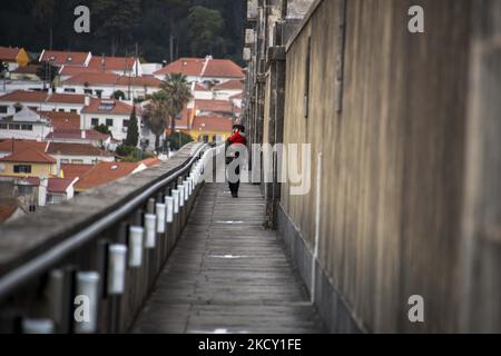 Die Menschen laufen entlang der Hauptstruktur des Aquädukts Aguas Livres, Lissabon. 05. Dezember 2021. Das Aquädukt Ãguas Livres oder das Freiwasser-Aquädukt ist eine von König Juan V. entworfene Struktur für die Trinkwasserverteilung in der Stadt Lissabon. Obwohl er im 19.. Jahrhundert fertiggestellt wurde, lieferte er bis 1748 Wasser in die Stadt.der Hauptkanal misst 19 km, Obwohl die Gesamtlänge einschließlich der Sekundärkanäle 58 km beträgt. Der bekannteste Teil sind die 35 Bögen über dem Tal, von denen der höchste 65 Meter hoch ist. Die öffentliche Straße über das Aquädukt ist seit 1853 gesperrt, par Stockfoto