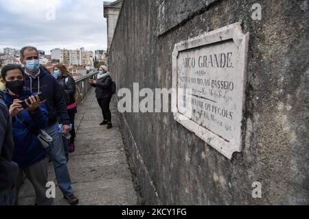 Die Menschen laufen entlang der Hauptstruktur des Aquädukts Aguas Livres, Lissabon. 05. Dezember 2021. Das Aquädukt Ãguas Livres oder das Freiwasser-Aquädukt ist eine von König Juan V. entworfene Struktur für die Trinkwasserverteilung in der Stadt Lissabon. Obwohl er im 19.. Jahrhundert fertiggestellt wurde, lieferte er bis 1748 Wasser in die Stadt.der Hauptkanal misst 19 km, Obwohl die Gesamtlänge einschließlich der Sekundärkanäle 58 km beträgt. Der bekannteste Teil sind die 35 Bögen über dem Tal, von denen der höchste 65 Meter hoch ist. Die öffentliche Straße über das Aquädukt ist seit 1853 gesperrt, par Stockfoto