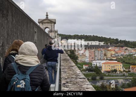 Die Menschen laufen entlang der Hauptstruktur des Aquädukts Aguas Livres, Lissabon. 05. Dezember 2021. Das Aquädukt Ãguas Livres oder das Freiwasser-Aquädukt ist eine von König Juan V. entworfene Struktur für die Trinkwasserverteilung in der Stadt Lissabon. Obwohl er im 19.. Jahrhundert fertiggestellt wurde, lieferte er bis 1748 Wasser in die Stadt.der Hauptkanal misst 19 km, Obwohl die Gesamtlänge einschließlich der Sekundärkanäle 58 km beträgt. Der bekannteste Teil sind die 35 Bögen über dem Tal, von denen der höchste 65 Meter hoch ist. Die öffentliche Straße über das Aquädukt ist seit 1853 gesperrt, par Stockfoto