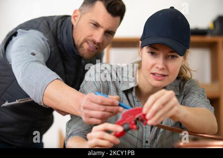 Lehrling der Klempnerin, die mit kupferrohren arbeitet Stockfoto