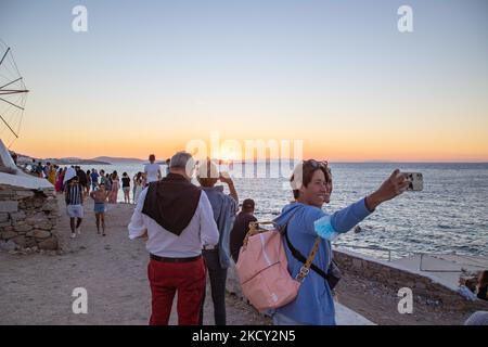 Die Menschen fotografieren den Sonnenuntergang von der Windmühlengegend in Mykonos Stadt. Touristen genießen einen wunderschönen Sonnenuntergang während der magischen Stunde auf der Insel Mykonos in Griechenland. Die griechische Insel Myconos ist ein beliebtes glamouröses mediterranes Reiseziel für einen Urlaub in den Kykladen, der Ägäis mit den ikonischen weiß getünchten Gebäuden, den Sandstränden und berühmten Partys an den Strandbars. Die Tourismus- und Reisebranche hatte aufgrund der Coronavirus-Pandemie Covid-19 negative Auswirkungen auf die Wirtschaft und die lokale Wirtschaft. Mykonos, Griechenland am 10. Oktober 2021 (Foto von Nicolas Economou/NurPhoto) Stockfoto