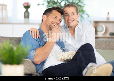 Glückliches Paar auf dem Sofa mit Popcorn beim Fernsehen Stockfoto