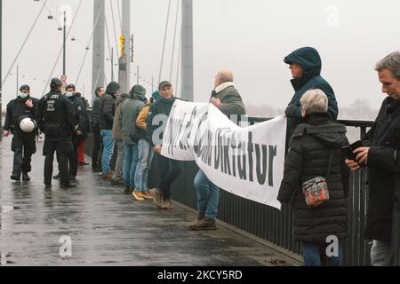 Polizeibeamte warnen die Demonstranten, das Banner während des Protests gegen die Impfpflicht und die Maßnahmen der Regierung in Düsseldorf am 18. Dezember 2021 von der Brücke zu entfernen (Foto: Ying Tang/NurPhoto) Stockfoto