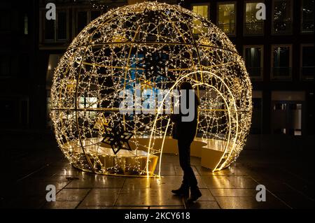 Ein Mann schaut auf eine große Lichtskulptur in Form eines Weihnachtsballs, die im Zentrum von Nijmegen aufgestellt wurde, um die Menschen während der härteren Sperre, die am selben Nachmittag, am 18.. Dezember, in Nijmegen, verhängt wurde, aufzumuntern. (Foto von Romy Arroyo Fernandez/NurPhoto) Stockfoto