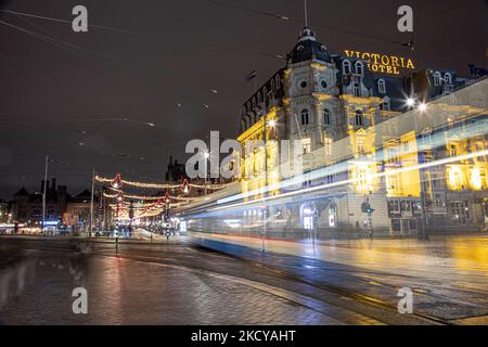 Die Straßenbahn fährt in Amsterdam vor dem Victoria Hotel ab. Straßen von Amsterdam am ersten Tag der plötzlichen Sperrung in der niederländischen Hauptstadt. Die erste europäische Nation erklärt eine vollständige Sperre, um gegen die neue Omicron-Variante zu kämpfen, die in die Höhe geht. Die Niederlande schließen, nachdem die Regierung die Schließung aller unwesentlichen Geschäfte, Cafés, Restaurants, Bars, Fitnessstudios, Schulen, Sportstätten, Kulturstätten und andere Orte ab Sonntag und für 4 Wochen, um die Ausbreitung der Omicron-Mutation des Covid-19-Coronavirus zu verhindern. Amsterdam, Niederlande am 19. Dezember 2021 (Foto: Nicolas Economou/N Stockfoto