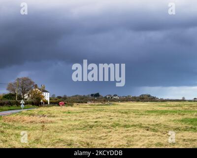 Dunkle Regenwolken über Port Carlisle an der Mündung des Solway in Cumbria, Großbritannien. Stockfoto