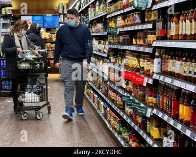 Mann, der am 23. Dezember 2021 beim Einkaufen in einem Lebensmittelgeschäft in Toronto, Ontario, Kanada, eine Gesichtsmaske trug. Ontario meldet in den letzten 24 Stunden eine Rekordzahl von 5.790 neuen COVID-19-Fällen, da die Omicron-Variante weiterhin einen Anstieg der Neuinfektionen auslöst. Dies ist die höchste Zahl von eintägigen Fällen, die jemals gemeldet wurde und übertrifft leicht die damals Rekordzahl von 4.812 Infektionen, die auf dem Höhepunkt der dritten Pandemie-Welle am 16. April bestätigt wurden. Schätzungsweise 87 Prozent aller Neuinfektionen stehen im Verdacht, durch die Omicron-Variante verursacht zu werden. Große Teile Kanadas beginnen sich zu treiben Stockfoto