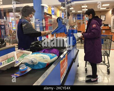 Kassierer in einem Walmart-Geschäft mit Gesichtsmaske während der neuartigen Coronavirus-Pandemie (COVID-19) in Markham, Ontario, Kanada, am 24. Dezember 2021. Ontario meldete am Freitag 9.571 neue COVID-19-Fälle und 6 neue Todesfälle, was alle bisherigen Infektionsrekorde während der gesamten Dauer der Pandemie erschütterte, während mehrere Beamte zugaben, dass das Testsystem der Provinz nicht mehr mithalten und die Ausbreitung der Infektion verfolgen kann. In ganz Ontario haben Gesundheitseinrichtungen, einschließlich derjenigen in Ottawa und London, Warnungen ausgegeben, dass der rechtzeitige Zugang zu PCR-Tests nicht mehr verfügbar ist. Das Gesundheitsministerium Stockfoto