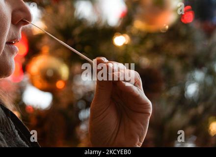 Eine Frau führt vor dem Weihnachtsbaum einen schnellen COVID-19-Antigentest durch, bevor sie sich ihrer Familie zum Weihnachtsessen anschließt. Das Rapid Response COVID-19 Antigen Rapid Test Device detektiert das Vorhandensein von SARS-CoV-2 viralen Nucleoprotein-Antigenen in nasalen und nasopharyngealen Sekreten. In nur 15 Minuten können Einzelpersonen ein positives oder negatives Ergebnis bestimmen. Am Freitag, den 24. Dezember 2021, Kanada. (Foto von Artur Widak/NurPhoto) Stockfoto