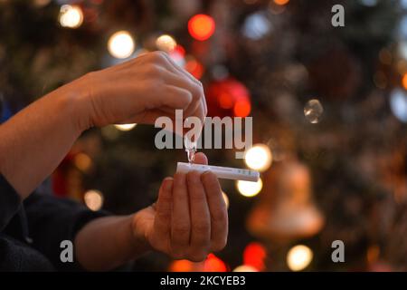 Eine Frau führt vor dem Weihnachtsbaum einen schnellen COVID-19-Antigentest durch, bevor sie sich ihrer Familie zum Weihnachtsessen anschließt. Das Rapid Response COVID-19 Antigen Rapid Test Device detektiert das Vorhandensein von SARS-CoV-2 viralen Nucleoprotein-Antigenen in nasalen und nasopharyngealen Sekreten. In nur 15 Minuten können Einzelpersonen ein positives oder negatives Ergebnis bestimmen. Am Freitag, den 24. Dezember 2021, Kanada. (Foto von Artur Widak/NurPhoto) Stockfoto