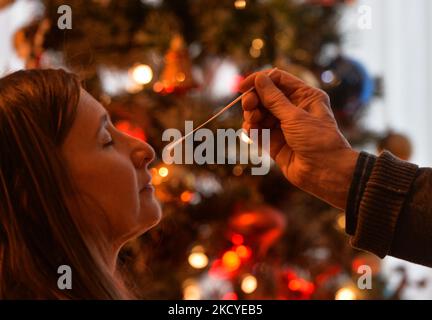 Eine Frau führt vor dem Weihnachtsbaum einen schnellen COVID-19-Antigentest durch, bevor sie sich ihrer Familie zum Weihnachtsessen anschließt. Das Rapid Response COVID-19 Antigen Rapid Test Device detektiert das Vorhandensein von SARS-CoV-2 viralen Nucleoprotein-Antigenen in nasalen und nasopharyngealen Sekreten. In nur 15 Minuten können Einzelpersonen ein positives oder negatives Ergebnis bestimmen. Am Freitag, den 24. Dezember 2021, Kanada. (Foto von Artur Widak/NurPhoto) Stockfoto