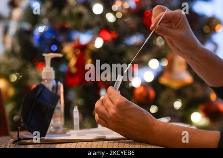 Eine Frau führt vor dem Weihnachtsbaum einen schnellen COVID-19-Antigentest durch, bevor sie sich ihrer Familie zum Weihnachtsessen anschließt. Das Rapid Response COVID-19 Antigen Rapid Test Device detektiert das Vorhandensein von SARS-CoV-2 viralen Nucleoprotein-Antigenen in nasalen und nasopharyngealen Sekreten. In nur 15 Minuten können Einzelpersonen ein positives oder negatives Ergebnis bestimmen. Am Freitag, den 24. Dezember 2021, Kanada. (Foto von Artur Widak/NurPhoto) Stockfoto