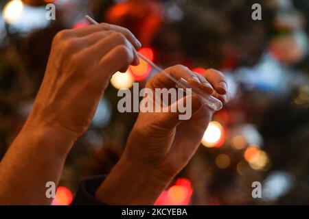 Eine Frau führt vor dem Weihnachtsbaum einen schnellen COVID-19-Antigentest durch, bevor sie sich ihrer Familie zum Weihnachtsessen anschließt. Das Rapid Response COVID-19 Antigen Rapid Test Device detektiert das Vorhandensein von SARS-CoV-2 viralen Nucleoprotein-Antigenen in nasalen und nasopharyngealen Sekreten. In nur 15 Minuten können Einzelpersonen ein positives oder negatives Ergebnis bestimmen. Am Freitag, den 24. Dezember 2021, Kanada. (Foto von Artur Widak/NurPhoto) Stockfoto