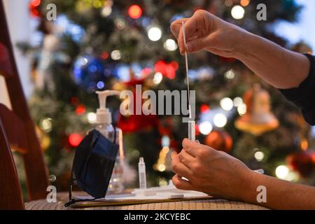 Eine Frau führt vor dem Weihnachtsbaum einen schnellen COVID-19-Antigentest durch, bevor sie sich ihrer Familie zum Weihnachtsessen anschließt. Das Rapid Response COVID-19 Antigen Rapid Test Device detektiert das Vorhandensein von SARS-CoV-2 viralen Nucleoprotein-Antigenen in nasalen und nasopharyngealen Sekreten. In nur 15 Minuten können Einzelpersonen ein positives oder negatives Ergebnis bestimmen. Am Freitag, den 24. Dezember 2021, Kanada. (Foto von Artur Widak/NurPhoto) Stockfoto