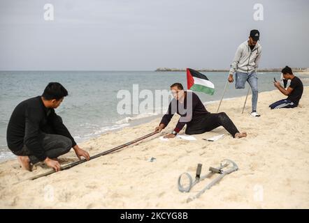 Ein Palästinenser Mohammed Totah ''32'', der am Strand von Gaza eine Sandzeichnung von 2022 anstellt und seine Hoffnung zum Ausdruck bringt, dass das neue Jahr das Friedensjahr Palästinas sein wird, am 28. Dezember 2021. Mohammed wurde nach israelischen Angriffen während des Gaza-Krieges am 28. Dezember 2008 im Führungskrieg gegen den Gazastreifen verletzt, der sein rechtes Bein verlor. Mohammed spricht über seine verheerende Verletzung, die sein Leben veränderte, ihn aber nicht von seinem Traum und seinem Streben nach einem guten Leben mit seiner Familie abgehalten hat. (Foto von Sameh Rahmi/NurPhoto) Stockfoto