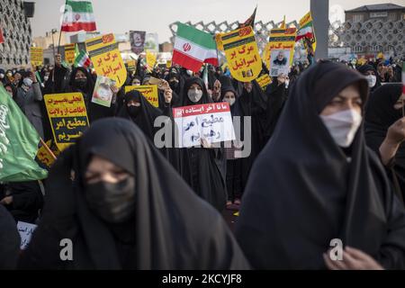 Eine iranische Frau hält ein Plakat mit persischen Schriftzeichen mit der Aufschrift: „Wir stehen bis zum Ende (Oben)“ und „Wir gehorchen dem Befehl des Führers“ während einer Kundgebung auf dem Imam-Hussein-Platz im Südosten Teherans am 30. Dezember 2021. Anhänger des iranischen Obersten Führers Ayatollah Ali Khamenei nehmen an einer Kundgebung zum Jahrestag der Demonstrationen gegen die Opposition im Dezember 2009 in Teheran Teil. (Foto von Morteza Nikoubazl/NurPhoto) Stockfoto