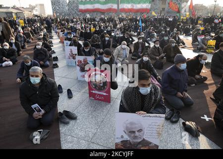 Iranische Männer, die Schutzmasken und palästinensische Tücher tragen, halten Porträts des ehemaligen Kommandanten des iranischen Korps der Islamischen Revolutionsgarde (IRGC) Quds Force, General Qasem Soleimani, der 2020 während eines US-Drohnenangriffs auf dem Internationalen Flughafen von Bagdad getötet wurde, Nehmen Sie am 30. Dezember 2021 an einer Kundgebung auf dem Imam-Hussein-Platz im Südosten Teherans Teil. Anhänger des iranischen Obersten Führers Ayatollah Ali Khamenei nehmen an einer Kundgebung zum Jahrestag der Demonstrationen gegen die Opposition im Dezember 2009 in Teheran Teil. (Foto von Morteza Nikoubazl/NurPhoto) Stockfoto