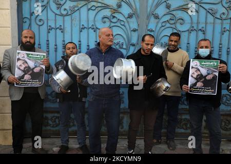 Palästinensische Demonstranten halten Bilder von Hisham Abu Hawasch, 40, Der sich seit mehr als 139 Tagen in einem Hungerstreik befindet, nachdem er von Israel verhaftet und in Verwaltungshaft genommen wurde, vor dem Büro des Hohen Kommissars der Vereinten Nationen für Menschenrechte in Gaza-Stadt, Sonntag, 2. Januar 2022. Verwandte von Abu Hawash sagten, dass er sich in einem kritischen Zustand in einem israelischen Krankenhaus befand. (Foto von Majdi Fathi/NurPhoto) Stockfoto