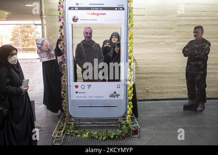 Iranische verschleierte Frauen posieren für Fotos mit einem Bildnis des iranischen obersten IRGC-Kommandanten, General Qasem Soleimani, der bei einem US-Drohnenangriff in Bagdad getötet wurde, Als Reaktion auf die Entfernung von Bildern des Generals Soleimani von den Instagram-Social-Seiten im Azadi (Freedom)-Sportkomplex, während sie am 1. Januar 2022 an einer Todeszeremonie von Soleimani im westlichen Teheran teilnahmen, stehen sie hinter einem Panel mit dem Logo des Instagram. Iran anlässlich des zweiten Todestages des ehemaligen Kommandanten des Korps der Islamischen Revolutionsgarde (IRGC) Quds Force, General Qasem Soleim Stockfoto