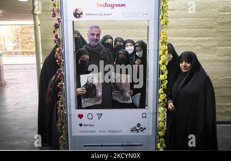 Iranische verschleierte Frauen posieren für Fotos mit einem Bildnis des iranischen obersten IRGC-Kommandanten, General Qasem Soleimani, der bei einem US-Drohnenangriff in Bagdad getötet wurde, Als Reaktion auf die Entfernung von Bildern des Generals Soleimani von den Instagram-Social-Seiten im Azadi (Freedom)-Sportkomplex, während sie am 1. Januar 2022 an einer Todeszeremonie von Soleimani im westlichen Teheran teilnahmen, stehen sie hinter einem Panel mit dem Logo des Instagram. Iran anlässlich des zweiten Todestages des ehemaligen Kommandanten des Korps der Islamischen Revolutionsgarde (IRGC) Quds Force, General Qasem Soleim Stockfoto