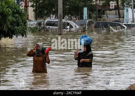 Man sieht, wie Menschen durch Überschwemmungen gehen, die durch einen überfließenden Fluss verursacht wurden, nachdem es am 2. Januar 2022 in Nord-Aceh, Provinz Aceh, Indonesien, schwere Regenfälle gab. (Foto von Fachrul Reza/NurPhoto) Stockfoto