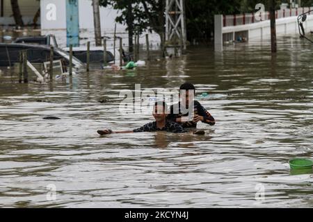 Man sieht, wie Menschen durch Überschwemmungen gehen, die durch einen überfließenden Fluss verursacht wurden, nachdem es am 2. Januar 2022 in Nord-Aceh, Provinz Aceh, Indonesien, schwere Regenfälle gab. (Foto von Fachrul Reza/NurPhoto) Stockfoto