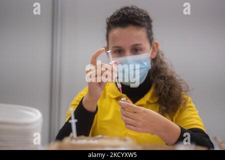 Eine GGD-Mitarbeiterin im Gesundheitswesen bereitet die Pfizer - BioNTech Covid-19-Impfstoffe vor, die sie aus der Fläschchenglasflasche zu den Spritzen im Sonderbereich des Mega-Impfzentrums in Eindhoven zieht. Die Jabs werden als Booster-Schuss verabreicht. Der dritte Dosisverstärker ist für alle in den Niederlanden verfügbar, zusätzlich zur Sperrung, da das Land gegen Ausbrüche der neuen omicron-Variante-Coronavirus-Mutation der Pandemie kämpft. Eindhoven, Niederlande am 7. Januar 2022 (Foto: Nicolas Economou/NurPhoto) Stockfoto