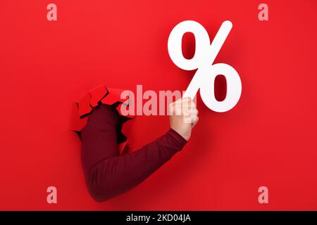 Hand hält Prozentzeichen über rotem Hintergrund Stockfoto