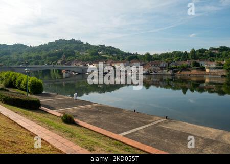 Blick über den ruhigen Fluss Lot in Richtung St-Sylvestre-sur-Lot Stadt und historischen Hügel Penne d'Agenais, Lot-et-Garonne, Frankreich vom Flussufer in Port de Penne (Penne d'Agenaise) bei Sommersonne. Stockfoto