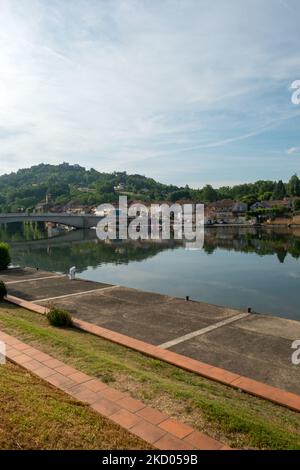 Blick über den ruhigen Fluss Lot in Richtung St-Sylvestre-sur-Lot Stadt und historischen Hügel Penne d'Agenais, Lot-et-Garonne, Frankreich vom Flussufer in Port de Penne (Penne d'Agenaise) bei Sommersonne. Stockfoto