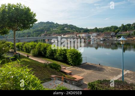 Blick über den ruhigen Fluss Lot in Richtung St-Sylvestre-sur-Lot Stadt und historischen Hügel Penne d'Agenais, Lot-et-Garonne, Frankreich vom Flussufer in Port de Penne (Penne d'Agenaise) bei Sommersonne. Stockfoto