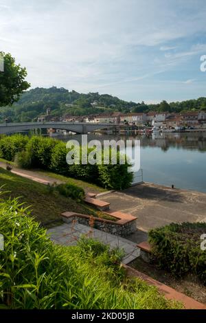 Blick über den ruhigen Fluss Lot in Richtung St-Sylvestre-sur-Lot Stadt und historischen Hügel Penne d'Agenais, Lot-et-Garonne, Frankreich vom Flussufer in Port de Penne (Penne d'Agenaise) bei Sommersonne. Stockfoto