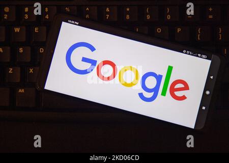 Google-Logo auf Smartphone-Display und eine Tastatur im Hintergrund. Google-Closeup-Logo auf einem Telefonbildschirm, Smartphone das Logo oder die Suchmaschine in verschiedenen Hintergründen wie Tastatur, dunkel beleuchtete Textur oder ein Computerbildschirm angezeigt, wie in dieser Multiple-Exposure-Illustration gesehen, das Unternehmenssymbol ist weltweit anerkannt. Google, LLC ist ein amerikanischer Tech-Gigant, ein multinationales Technologieunternehmen, das sich auf internetbezogene Dienste und Produkte spezialisiert hat, zu denen Online-Werbetechnologien, eine Suchmaschine, Cloud-Computing, Software und Hardware gehören. Es gilt als eines der t Stockfoto