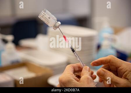 Nahaufnahme der Spritze, der Ampulle und der Hände einer Frau, die den Booster-Shot vorbereitet. GGD, Mitarbeiter im öffentlichen Gesundheitswesen, bereitet die Impfstoffe der Moderna Spikevax mRNA Covid-19 vor, die sie aus der Glasflasche in Fläschchen zu individuellen Dosen in den Spritzen im Sondergebiet des Mega-Impfzentrums in Eindhoven ziehen. Die Jabs werden als Booster-Schuss verabreicht. Der dritte Dosisverstärker ist für alle in den Niederlanden verfügbar, zusätzlich zur Sperrung, da das Land gegen Ausbrüche der neuen omicron-Variante-Coronavirus-Mutation der Pandemie kämpft. Eindhoven, Niederlande am 7. Januar 2022 (Foto: N Stockfoto