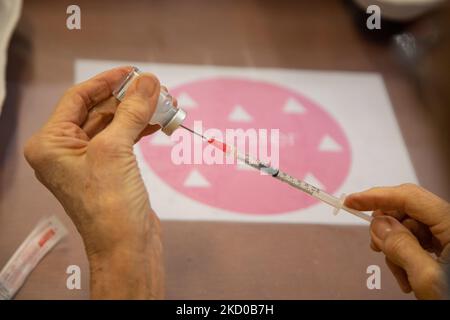 Nahaufnahme der Spritze, der Ampulle und der Hände einer Frau, die den Booster-Shot vorbereitet. GGD, Mitarbeiter im öffentlichen Gesundheitswesen, bereitet die Impfstoffe der Moderna Spikevax mRNA Covid-19 vor, die sie aus der Glasflasche in Fläschchen zu individuellen Dosen in den Spritzen im Sondergebiet des Mega-Impfzentrums in Eindhoven ziehen. Die Jabs werden als Booster-Schuss verabreicht. Der dritte Dosisverstärker ist für alle in den Niederlanden verfügbar, zusätzlich zur Sperrung, da das Land gegen Ausbrüche der neuen omicron-Variante-Coronavirus-Mutation der Pandemie kämpft. Eindhoven, Niederlande am 7. Januar 2022 (Foto: N Stockfoto