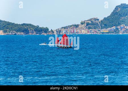 Altes Segelboot mit drei roten Segeln im blauen Mittelmeer vor der berühmten Stadt Porto Venere oder Portovenere, UNESCO-Weltkulturerbe, G Stockfoto